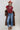 A woman wearing a long,  brown faux fur coat with a horse motif lining, paired with a rust-colored cowboy hat, a maroon tigher patterned top, and blue jeans against a gray background-Longline_Faux_Fur_Jacket_-_Brown-FleaStyle