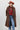A woman wearing a long,  brown faux fur coat with a horse motif lining, paired with a rust-colored cowboy hat, a maroon tigher patterned top, and blue jeans against a gray background-Longline_Faux_Fur_Jacket_-_Brown-FleaStyle