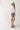 Woman wearing a pink shirt, High Rise Frayed Hem A Line Denim Shorts, and cowboy boots on a white background