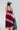 A woman wearing a  maxi dress in deep burgundy with light pink floral lace trim, styled with a dusty blue cowboy hat and holding a blue denim jacket against a plain white studio background.-Lace_Trim_Maxi_Dress_-_Blush_Maroon-FleaStyle