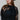 A woman wearing a sheer black lace top in a flowy silhouette, scalloped detailing and an oversized bow and a high ruffled collar, paired with dusty blue cowboy hat and blue jeans, against a plain light gray background-Sheer Lace Tie Neck Blouse - Black