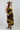 A woman  wearing a chocolate  brown maxi dress with olive green lace trim, styled with a stone/beige cowboy hat and brown boots -Lace_Trim_Maxi_Dress_-_Brown_Chartreuse-FleaStyle