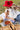Woman in a red hat sitting on a blanket with a picnic setup in a grassy area.