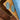 A pair of oval silver-toned concho style earrings with turquoise-colored inlay stones, displayed on a wooden surface next to a blue fabric-Western_Inspired_Scalloped_Earrings-FleaStyle.