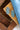 A pair of oval silver-toned concho style earrings with turquoise-colored inlay stones, displayed on a wooden surface next to a blue fabric-Western_Inspired_Scalloped_Earrings-FleaStyle.