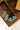  A pair of silver stud earrings with five turquoise-colored stones each, displayed on a tan book next to a blue fabric surface-Faux_Turquoise_Cluster_Stud_Earrings-FleaStyle.