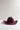 A dark burgundy felt cowboy hat with a wide brim, photographed on a clean white surface against a light gray background.