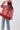 A woman wearing a red paisley jacket featuring an easy, relaxed silhouette with quilted detailing, contrasting stitching and beautiful lace appliqués that give it a cool, collected-over-time feel-Quilted_Jacket_with_Paisley_Patches_-_Red-FleaStyle