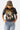 A woman wearing a washed black vintage inspired graphic t-shirt with a "DOLLY" portrait print, paired with light blue jeans and an olive baseball cap with 'Texas' written on it, posed against a solid light gray background-Dolly_Portrait_Graphic_T-Shirt_-_Washed_Black-FleaStyle