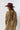 A woman wearing a bohemian-style leopard print dress featuring a flowy high-low silhouette, peek-a-boo sleeves, a maroon cowboy hat, and brown cowboy boots, photographed against a solid white background-Animal_Print_High-Low_Chiffon_Dress-FleaStyle