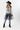 A woman wearing a western-style outfit featuring a white long-sleeve button-up shirt, a sheer black mesh overlay, featuring a relaxed, sleeveless fit and a flowy tulle hem, blue jeans, a black cowboy hat, and black ankle boots, against a plain white studio background-Sleeveless_Sheer_Mesh_Overlay_-_Black