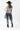 A woman wearing a western-style outfit featuring a white long-sleeve button-up shirt, a sheer black mesh overlay, featuring a relaxed, sleeveless fit and a flowy tulle hem, blue jeans, a black cowboy hat, and black ankle boots, against a plain white studio background-Sleeveless_Sheer_Mesh_Overlay_-_Black-FleaStyle