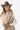 A smiling woman wearing a brown cowboy hat, a beige sleeveless vest with robe tie and oversized faux-fur collar, jeans and a white long-sleeve top, photographed against a clean white studio background-Fur Trimmed Sleeveless Duster Vest - Taupe