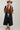 A woman wearing a pintuck shirt dress features a collared neckline, button-front design, defined tie waist and a flowy midi silhouette with a brown straw cowboy hat, a rust-brown ruffled blouseand light-wash blue jeans-Pintuck Waist Tie Front Midi Dress/Duster - Black