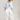 A model wearing a light blue knit short-sleeve top, modern barrel-leg silhouette, adjustable drawstring waist and utility-inspired seaming for a relaxed yet elevated fit, a brown straw cowboy hat, and blue boots--Drawstring_Barrel_Jogger_Pants_-_Ivory-FleaStyle