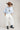 A model wearing a light blue knit short-sleeve top, modern barrel-leg silhouette, adjustable drawstring waist and utility-inspired seaming for a relaxed yet elevated fit, a brown straw cowboy hat, and blue boots--Drawstring_Barrel_Jogger_Pants_-_Ivory-FleaStyle