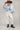A model wearing a light blue knit short-sleeve top, modern barrel-leg silhouette, adjustable drawstring waist and utility-inspired seaming for a relaxed yet elevated fit, a brown straw cowboy hat, and blue boots--Drawstring_Barrel_Jogger_Pants_-_Ivory-FleaStyle
