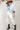 A model wearing a light blue knit short-sleeve top, modern barrel-leg silhouette, adjustable drawstring waist and utility-inspired seaming for a relaxed yet elevated fit, a brown straw cowboy hat, and blue boots--Drawstring_Barrel_Jogger_Pants_-_Ivory-FleaStyle
