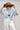 A model wearing a light blue knit short-sleeve top, modern barrel-leg silhouette, adjustable drawstring waist and utility-inspired seaming for a relaxed yet elevated fit, a brown straw cowboy hat, and blue boots--Drawstring_Barrel_Jogger_Pants_-_Ivory-FleaStyle