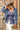 A woman wearing a strapless blue corset-style top with gold-tone buckle clasps, a long satin maxi skirt with a colorful printed  horse design, paired with a beige cowboy hat and dark blue boots, against studio background-Western_Buckle_Strapless_Top_-_Dusty_Blue-FleaStyle