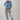 A woman wearing a light blue cropped denim shaket and high-waisted pant with allover snakeskin print with shimmering sequin detailing and an easy straight-leg silhouette, styled with an  ivory cowboy hat and gold jewelry against a light gray studio background--Sequin_Snakeskin_Print_Wide_Leg_Pants-FleaStyle