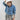 A woman wearing a light blue cropped denim relaxed denim shirt-jacket, an ivory cowboy hat, and high-waisted pant with allover snakeskin print and shimmering sequins--Cropped_Denim_Shacket-FleaStyle