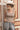A woman wearing  an ivory cowboy hat, and wide-leg patterned pants and a form-fitting tank featuring a flattering scoop neckline with studded detailing for a subtle western edge-Studded Knit Tank Top - Tan-FleaStyle
