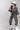 A woman wearing a charcol button-down shirt an allover leopard print with an easy barrel-leg silhouette, utility-inspired pockets and a rope tie waist, paired with a white trucker hat and silver boots, against a light gray studio background--Leopard_Print_Barrel_Jeans-FleaStyle