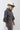 A woman wearing a charcoal gray oversized button-down shirt with a relaxed fit, voluminous sleeves and a soft bubble hem, leopard-print wide-leg jeans, silver cowboy boots, and a Texas trucker hat --Bubble_Sleeve_Button_Down_Top_-_Charcoal_Gray-FleaStyle