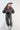 A woman wearing a charcoal gray oversized button-down shirt with a relaxed fit, voluminous sleeves and a soft bubble hem, leopard-print wide-leg jeans, silver cowboy boots, and a Texas trucker hat --Bubble_Sleeve_Button_Down_Top_-_Charcoal_Gray-FleaStyle