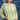 A woman wearing a lime green ribbed long-sleeve crewneck shirt with 'TEXAS' printed in white block letters across the chest, paired with denim shorts and a camouflage baseball cap, standing against a blue denim patchwork backdrop-Fleastyle