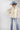 A woman wearing a cream blouse with dark polka dots, mid-rise cropped jeans with a silhouette fit through the hips and thighs and easy kick flare, and a dusty  blue cowboy hat-Mid-Rise_Cropped_Bootcut_Jeans-FleaStyle.