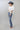A woman wearing a white short-sleeve crop top with a lace sheer underlay in a delicate floral pattern, with fitted silhouette and thumb holes, blue jeans, and a dusty blue cowboy hat -Lace_Mock_Neck_Sheer_Underlay_-_Beige-FleaStyle