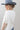 A woman wearing a white short-sleeve crop top with a lace sheer underlay in a delicate floral pattern, with fitted silhouette and thumb holes, blue jeans, and a dusty blue cowboy hat -Lace_Mock_Neck_Sheer_Underlay_-_Beige-FleaStyle
