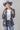 A woman wearing a western-style outfit featuring a playful Western Embroidered Patch Blazer with colorful embroidered patches, a dusty blue cowboy hat, denim denim jeans, and silver cowboy boots --Western_Embroidered_Patch_Blazer-FleaStyle