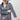 A woman wearing a western-style outfit featuring a playful Western Embroidered Patch Blazer with colorful embroidered patches, a dusty blue cowboy hat, denim denim jeans, and silver cowboy boots --Western_Embroidered_Patch_Blazer-FleaStyle