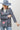 A woman wearing a western-style outfit featuring a playful Western Embroidered Patch Blazer with colorful embroidered patches, a dusty blue cowboy hat, denim denim jeans, and silver cowboy boots --Western_Embroidered_Patch_Blazer-FleaStyle