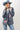 A woman wearing a western-style outfit featuring a playful Western Embroidered Patch Blazer with colorful embroidered patches, a dusty blue cowboy hat, denim denim jeans, and silver cowboy boots --Western_Embroidered_Patch_Blazer-FleaStyle