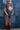 Woman in a trucker hat, Choosin' Texas Graphic T-Shirt - Pink- denim shorts and cowboy boots in front of a denim patchwork background-Fleastyle