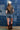 Woman in a trucker hat, Choosin' Texas Graphic T-Shirt - Pink- denim shorts and cowboy boots in front of a denim patchwork background-Fleastyle