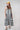 A woman modeling a sleeveless midi dress with bold black and white vertical stripes, paired with a yellow trucker hat and patterned shoes-Vertical Stripe Midi Dress - Black/Ivory