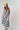 A woman modeling a sleeveless midi dress with bold black and white vertical stripes, paired with a yellow trucker hat and patterned shoes-Vertical Stripe Midi Dress - Black/Ivory