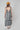 A woman modeling a sleeveless midi dress with bold black and white vertical stripes, paired with a yellow trucker hat and patterned shoes-Vertical Stripe Midi Dress - Black/Ivory