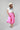 A woman wearing a bright pink pleated midi skirt with a white graphic t-shirt and an ivory cowboy hat-A-Line Midi Skirt - Hot Pink-FleaStyle