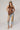 A woman  a brown lace camisole top, light blue patchwork jeans with floral patches, an olive baseball cap, and brown strappy heelsFleaStyle