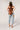A woman  a brown lace camisole top, light blue patchwork jeans with floral patches, an olive baseball cap, and brown strappy heelsFleaStyle