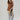 A woman  a brown lace camisole top, light blue patchwork jeans with floral patches, an olive baseball cap, and brown strappy heelsFleaStyle