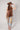 A woman  a brown lace camisole top, light blue patchwork jeans with floral patches, an olive baseball cap, and brown strappy heelsFleaStyle