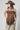 A woman  a brown lace camisole top, light blue patchwork jeans with floral patches, an olive baseball cap, and brown strappy heelsFleaStyle