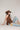 A woman  a brown lace camisole top, light blue patchwork jeans with floral patches, an olive baseball cap, and brown strappy heelsFleaStyle